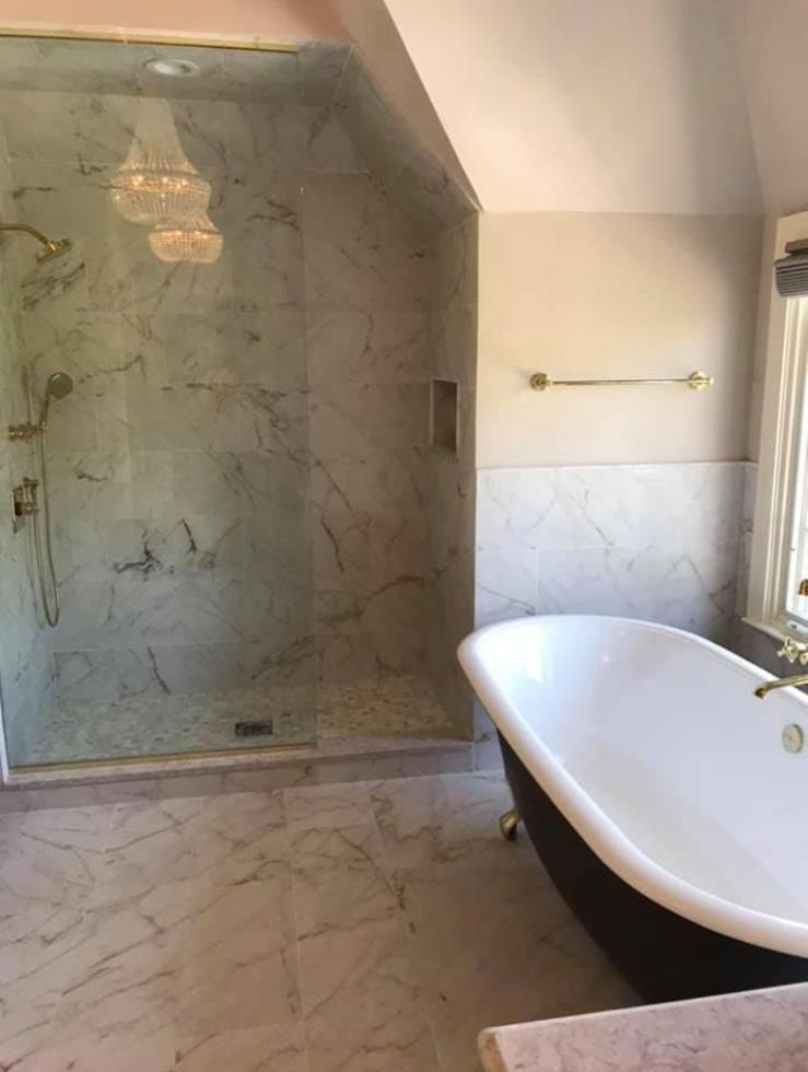 Marble shower and clawfoot tub with brass fixtures