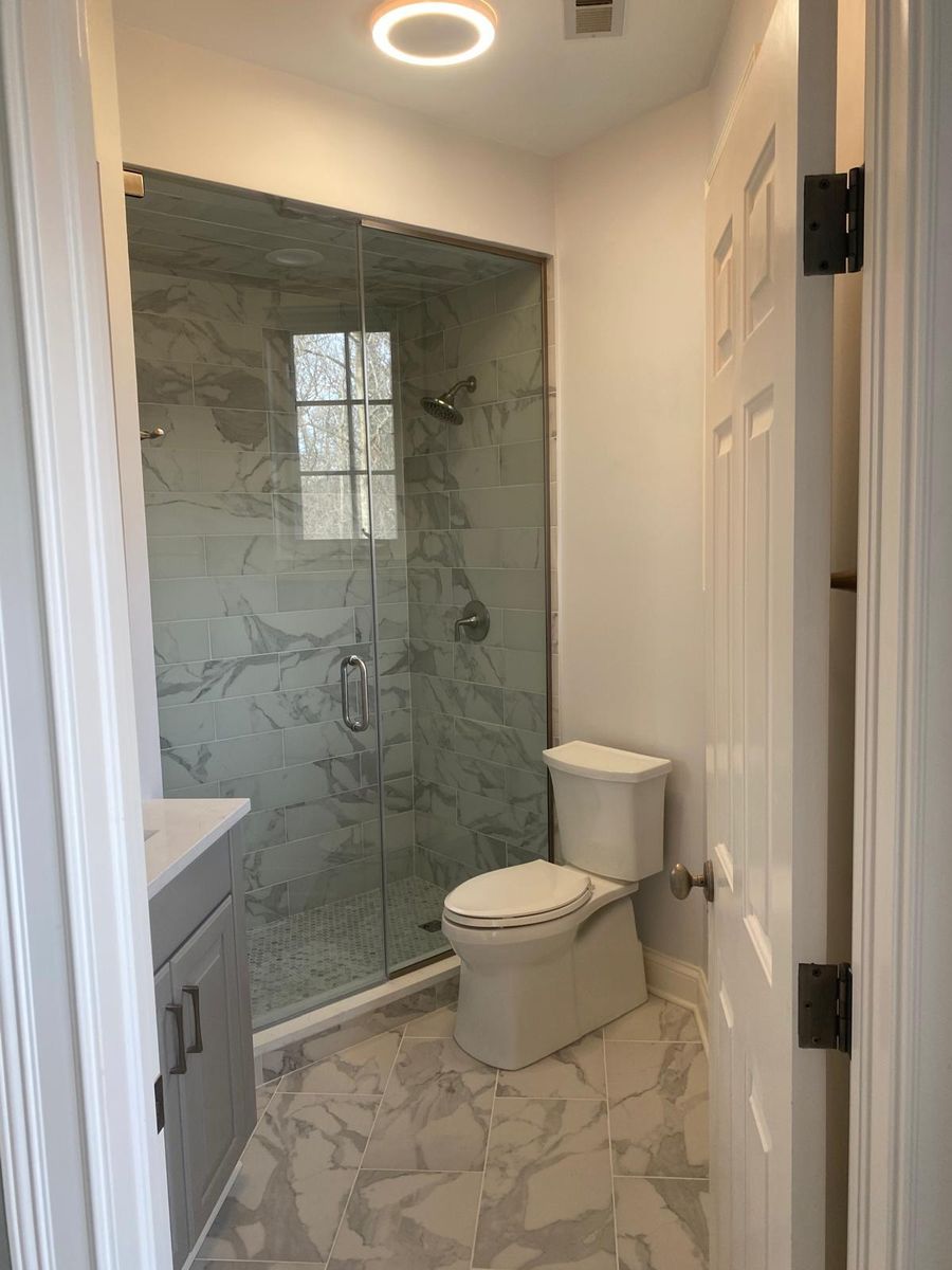 Bathroom with glass shower enclosure and marble look floor